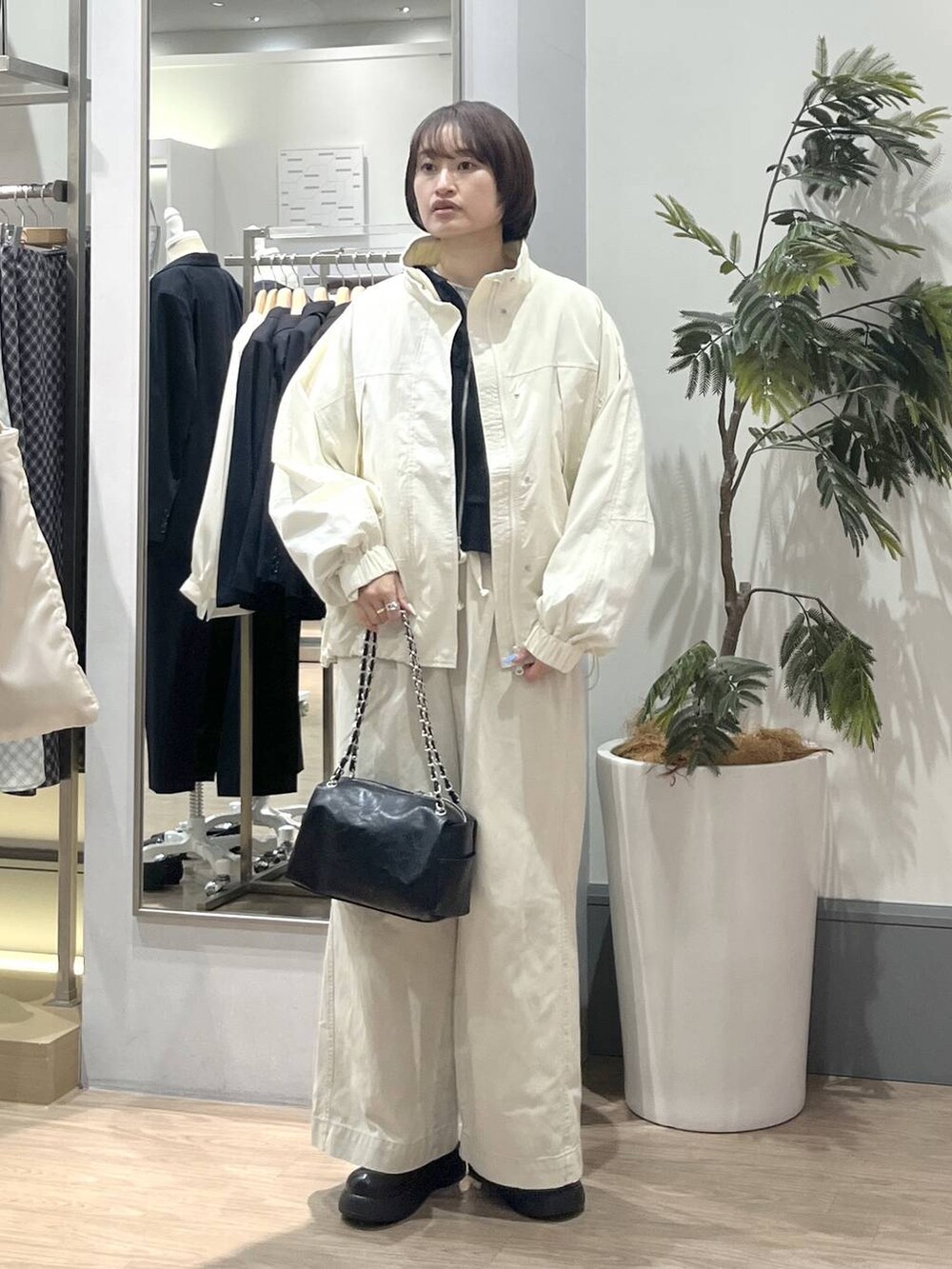 ホワイト系のナイロンジャケット、ホワイト系のデニムパンツ、ブラック系のショルダーバッグを着用したレディースの冬コーディネートの2枚目の写真