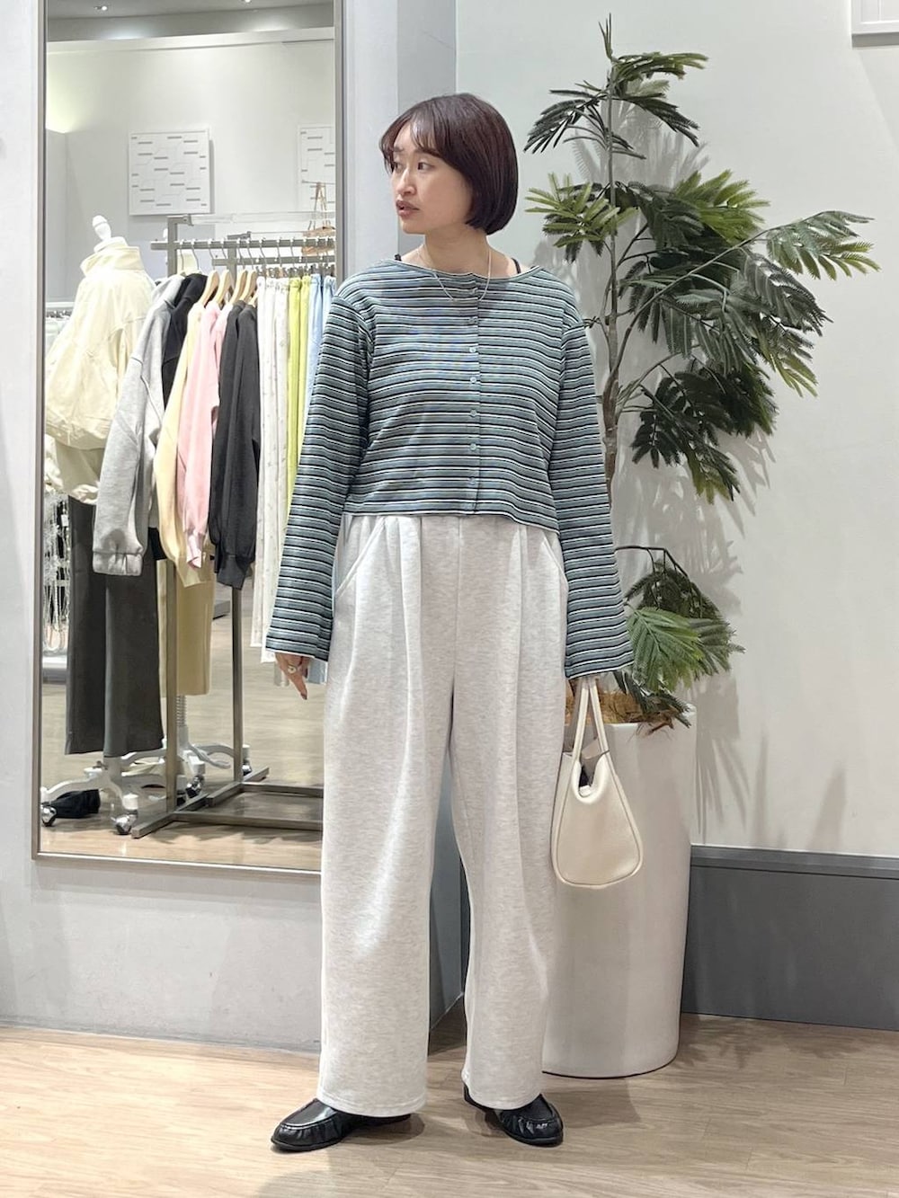 ブラック系のTシャツ/カットソー、グレー系のスウェットパンツ、ホワイト系のショルダーバッグを着用したレディースの春コーディネートの2枚目の写真