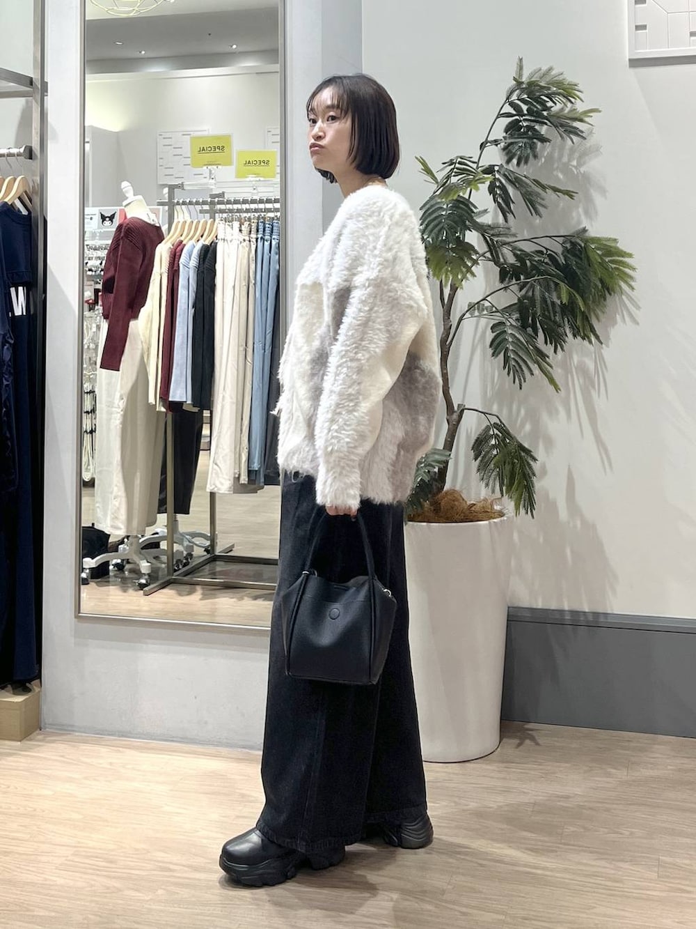 ブラック系のブーツ、ホワイト系のカーディガン/ボレロ、ホワイト系のTシャツ/カットソーを着用したレディースの秋コーディネートの4枚目の写真