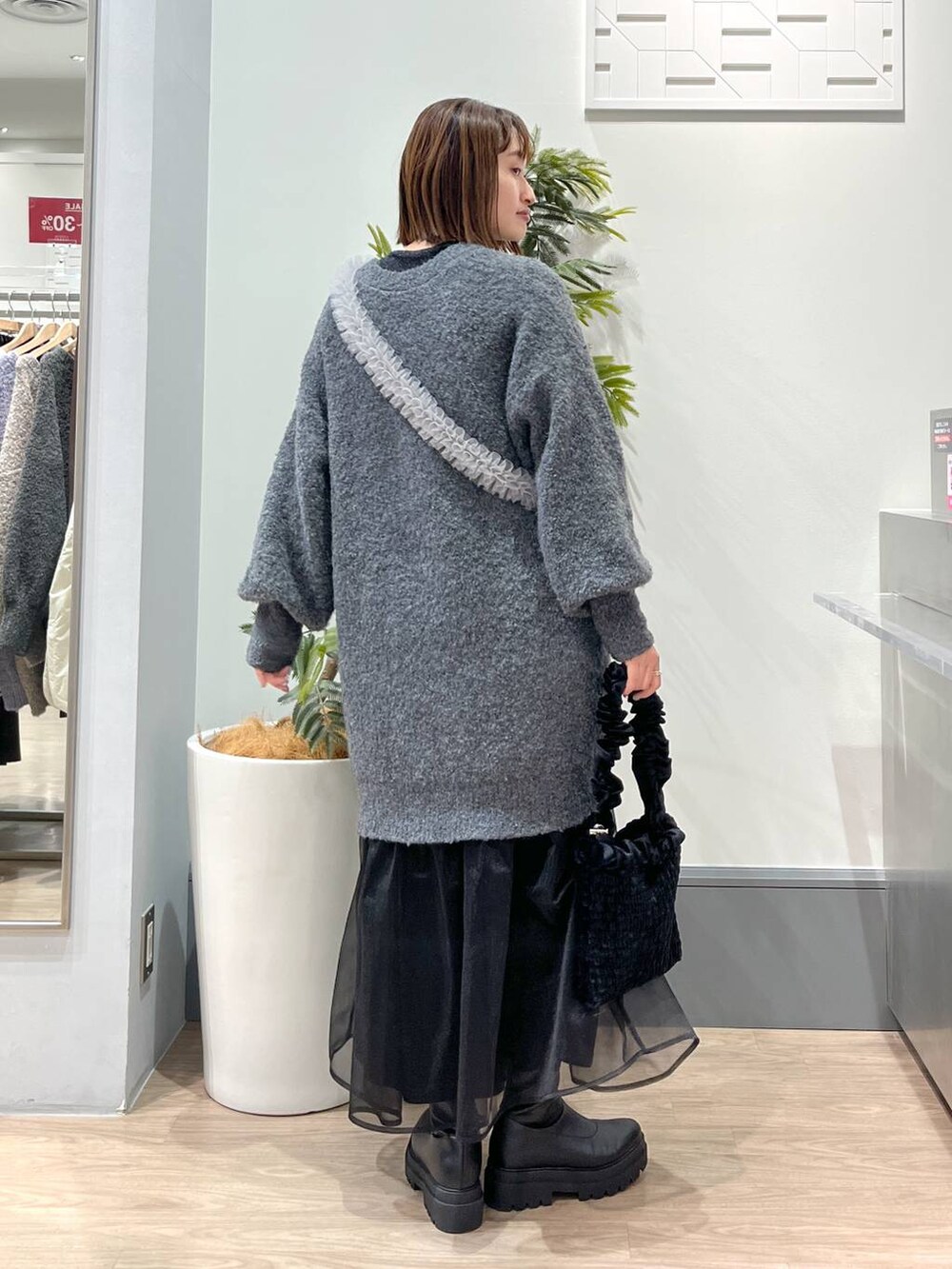 グレー系のチュニック、ブラック系のブーツ、ブラック系のショルダーバッグを着用したレディースの冬コーディネートの4枚目の写真