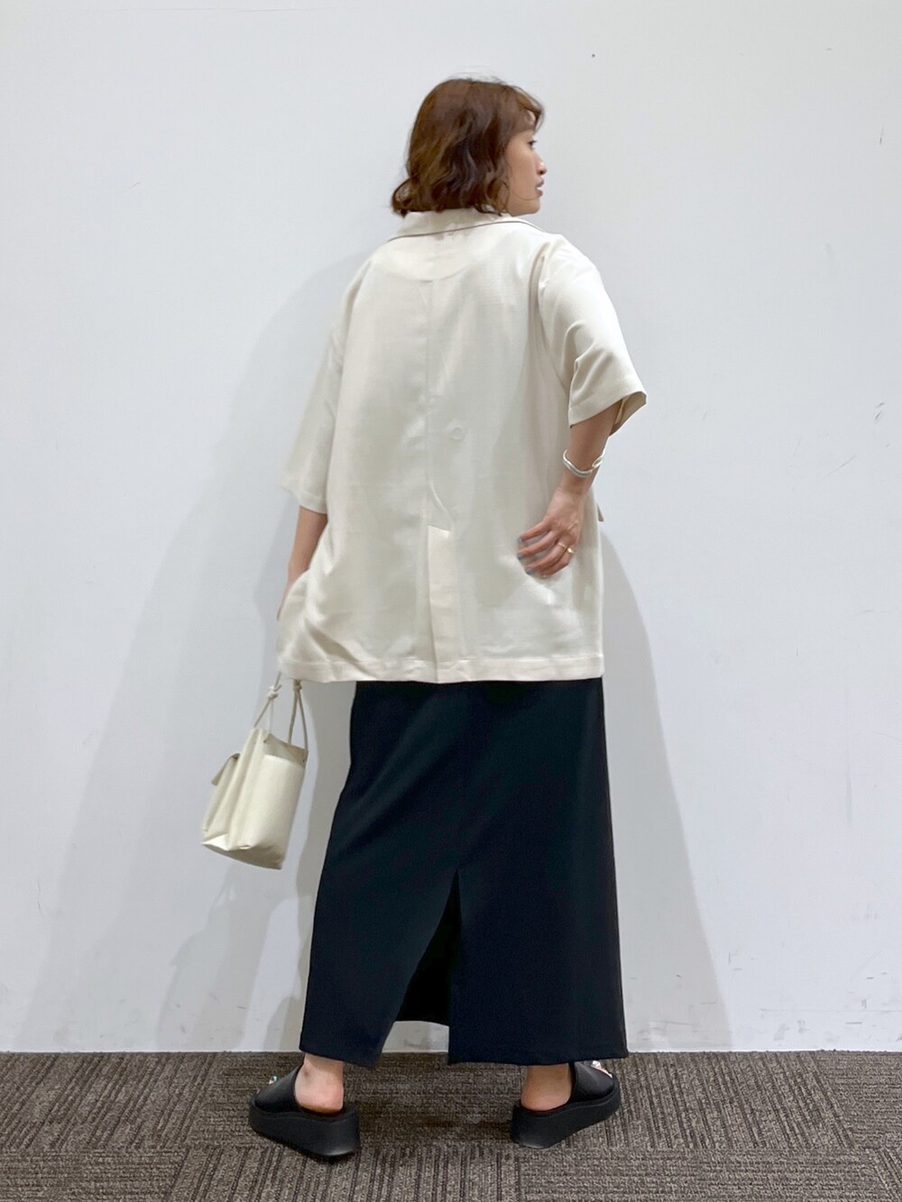 ホワイト系のテーラードジャケット、ブラック系のトップス、ブラック系のワンピースを着用したレディースの春コーディネートの3枚目の写真