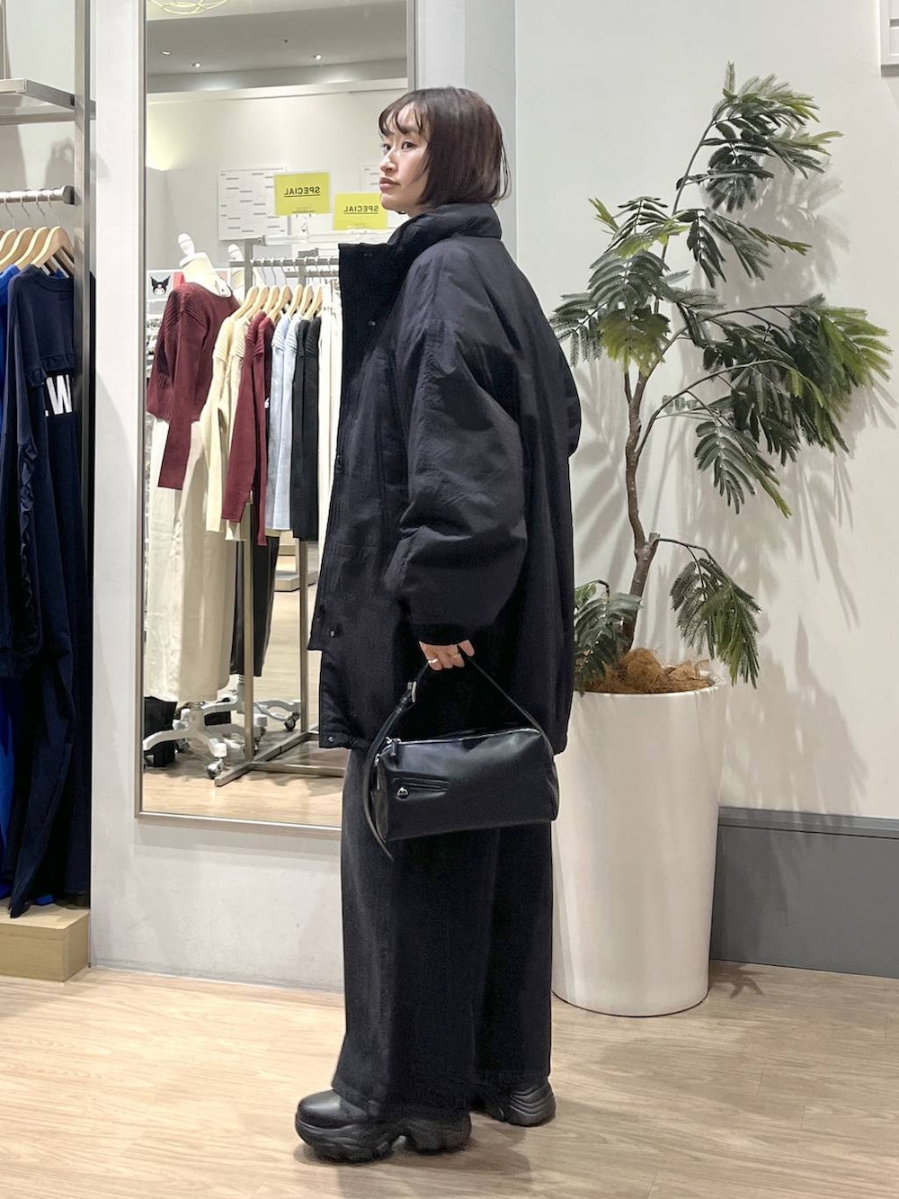 ブラック系のブーツ、ブラック系のショルダーバッグ、ブラック系のデニムパンツを着用したレディースの秋コーディネートの3枚目の写真