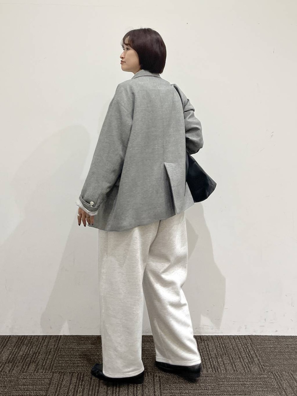 ブラック系のショルダーバッグ、グレー系のスウェットパンツ、グレー系のテーラードジャケットを着用したレディースの春コーディネートの5枚目の写真