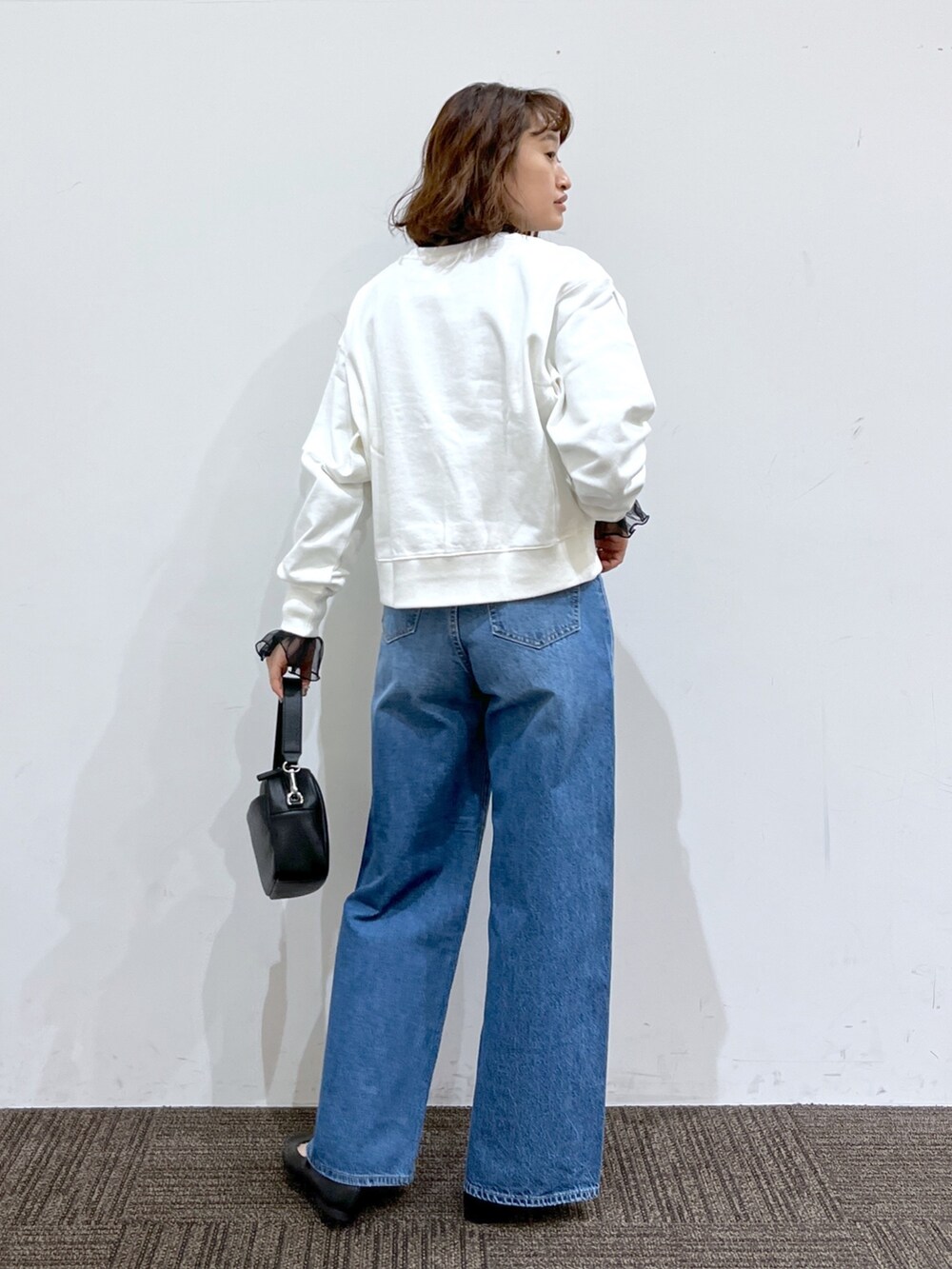 ブラック系のトップス、ホワイト系のトップス、ブルー系のパンツを着用したレディースの冬コーディネートの3枚目の写真