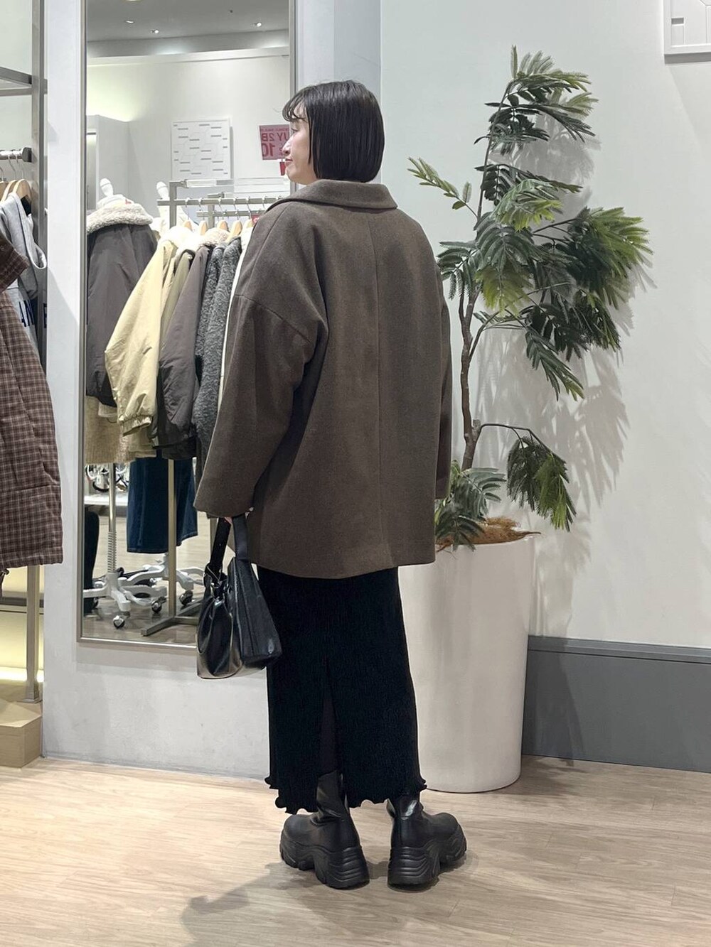 ホワイト系のニット/セーター、ブラック系のブーツ、ブラック系のスカートを着用したレディースの冬コーディネートの4枚目の写真