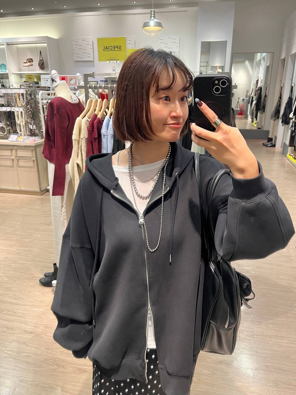 ブラック系のスカート、ブラック系のパーカー、ホワイト系のTシャツ/カットソーを着用したレディースの秋コーディネートの4枚目の写真