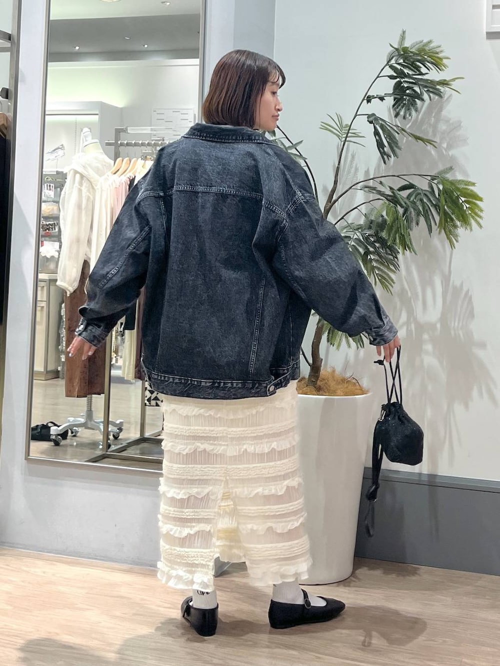 ホワイト系のTシャツ/カットソー、ホワイト系のスカート、ブラック系のデニムジャケットを着用したレディースの秋コーディネートの4枚目の写真