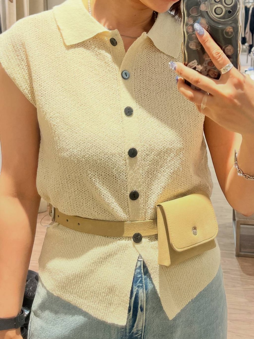 ホワイト系のベスト、ブルー系のデニムパンツ、ベージュ系のベルトを着用したレディースの夏コーディネートの5枚目の写真