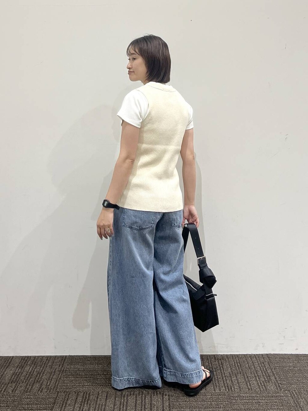 ブルー系のデニムパンツ、ホワイト系のTシャツ/カットソー、ブラック系のサンダルを着用したレディースの夏コーディネートの5枚目の写真
