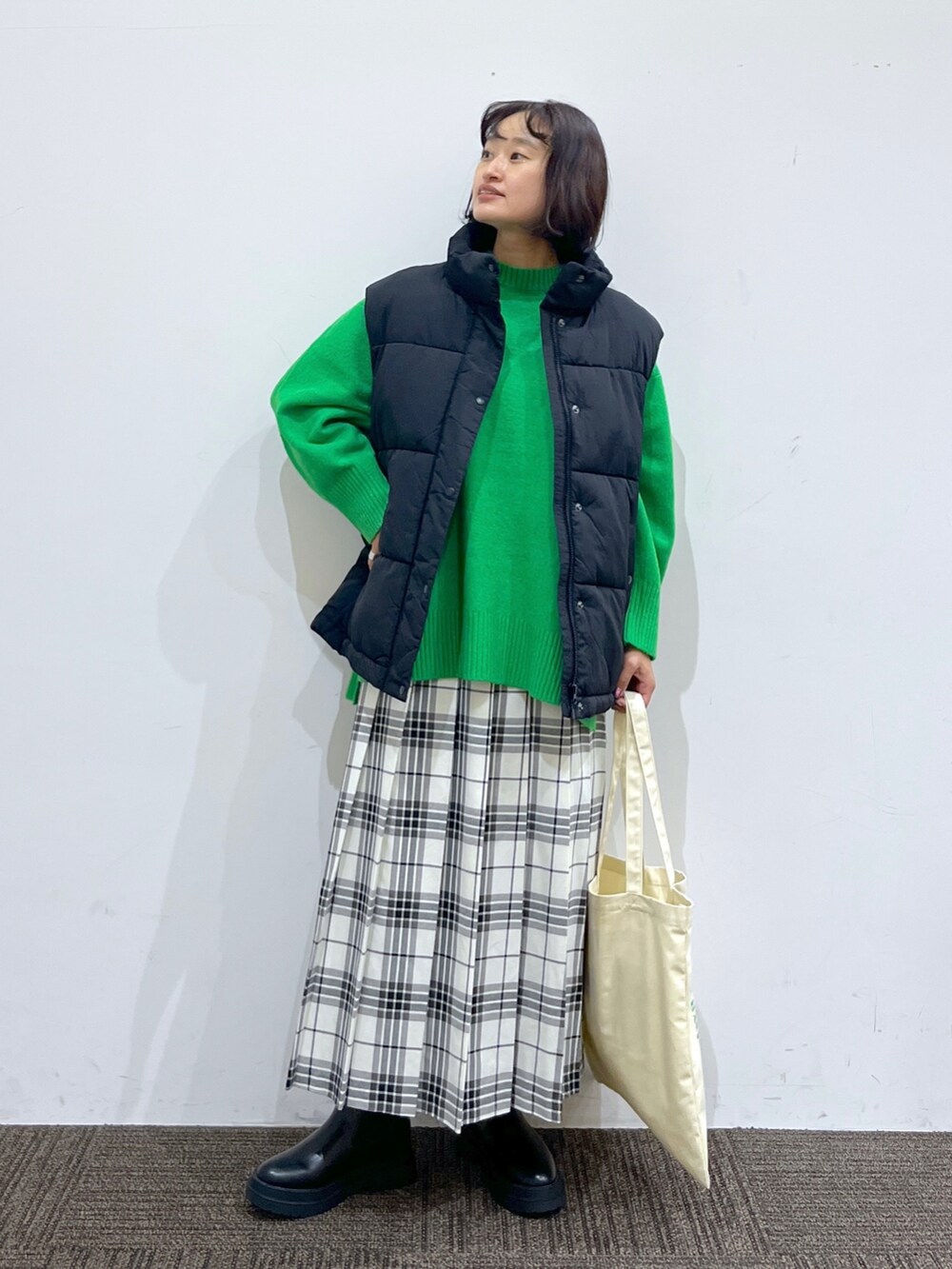 ブラック系のブーツ、ホワイト系のバッグ、ホワイト系のスカートを着用したレディースの秋コーディネートの2枚目の写真