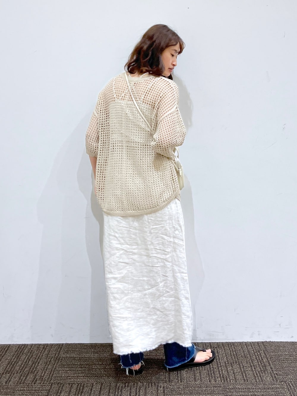 ブルー系のデニムパンツ、ホワイト系のスカート、ホワイト系のショルダーバッグを着用したレディースの春コーディネートの3枚目の写真