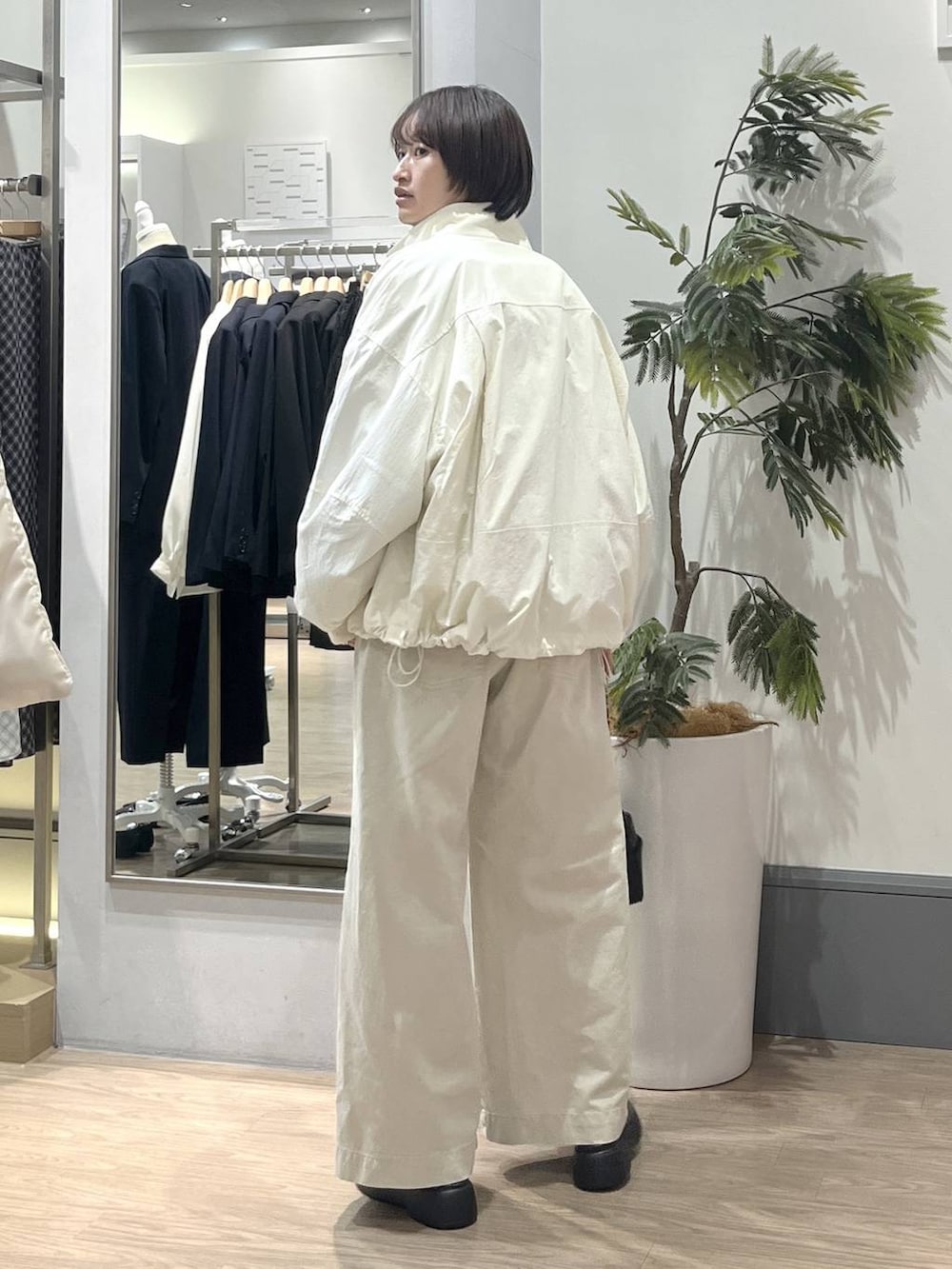 ホワイト系のナイロンジャケット、ホワイト系のデニムパンツ、ブラック系のショルダーバッグを着用したレディースの冬コーディネートの4枚目の写真