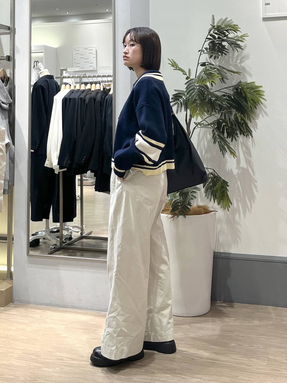 ブラック系のショルダーバッグ、ブラック系のTシャツ/カットソー、ホワイト系のデニムパンツを着用したレディースの冬コーディネートの3枚目の写真