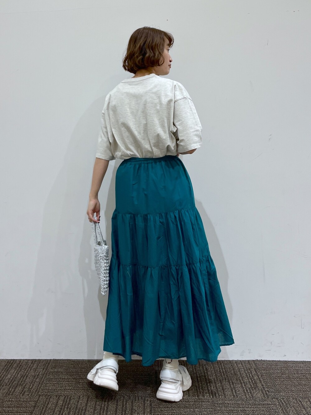 グレー系のTシャツ/カットソー、グリーン系のスカート、シルバー系のバッグを着用したレディースの春コーディネートの3枚目の写真