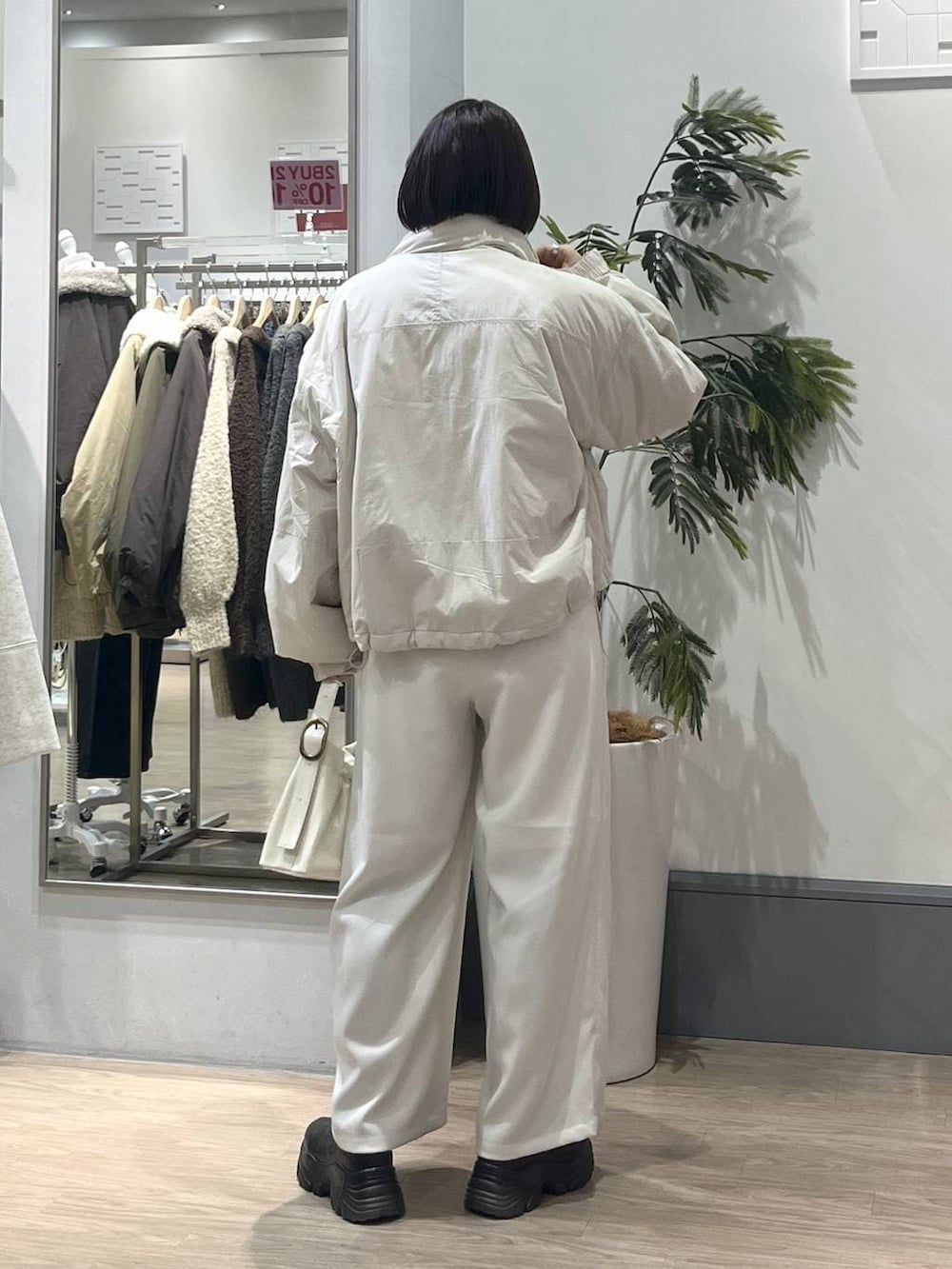 ホワイト系のその他アウター、ブラック系のブーツ、ホワイト系のニット/セーターを着用したレディースの冬コーディネートの4枚目の写真