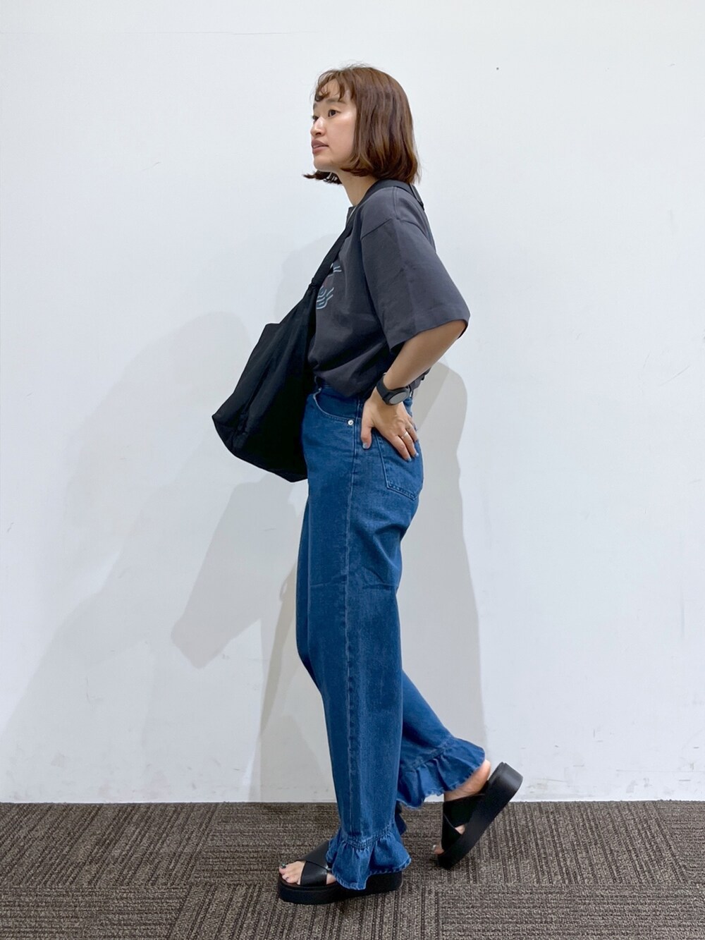 ブルー系のデニムパンツ、グレー系のTシャツ/カットソー、ブラック系のバッグを着用したレディースの春コーディネートの2枚目の写真