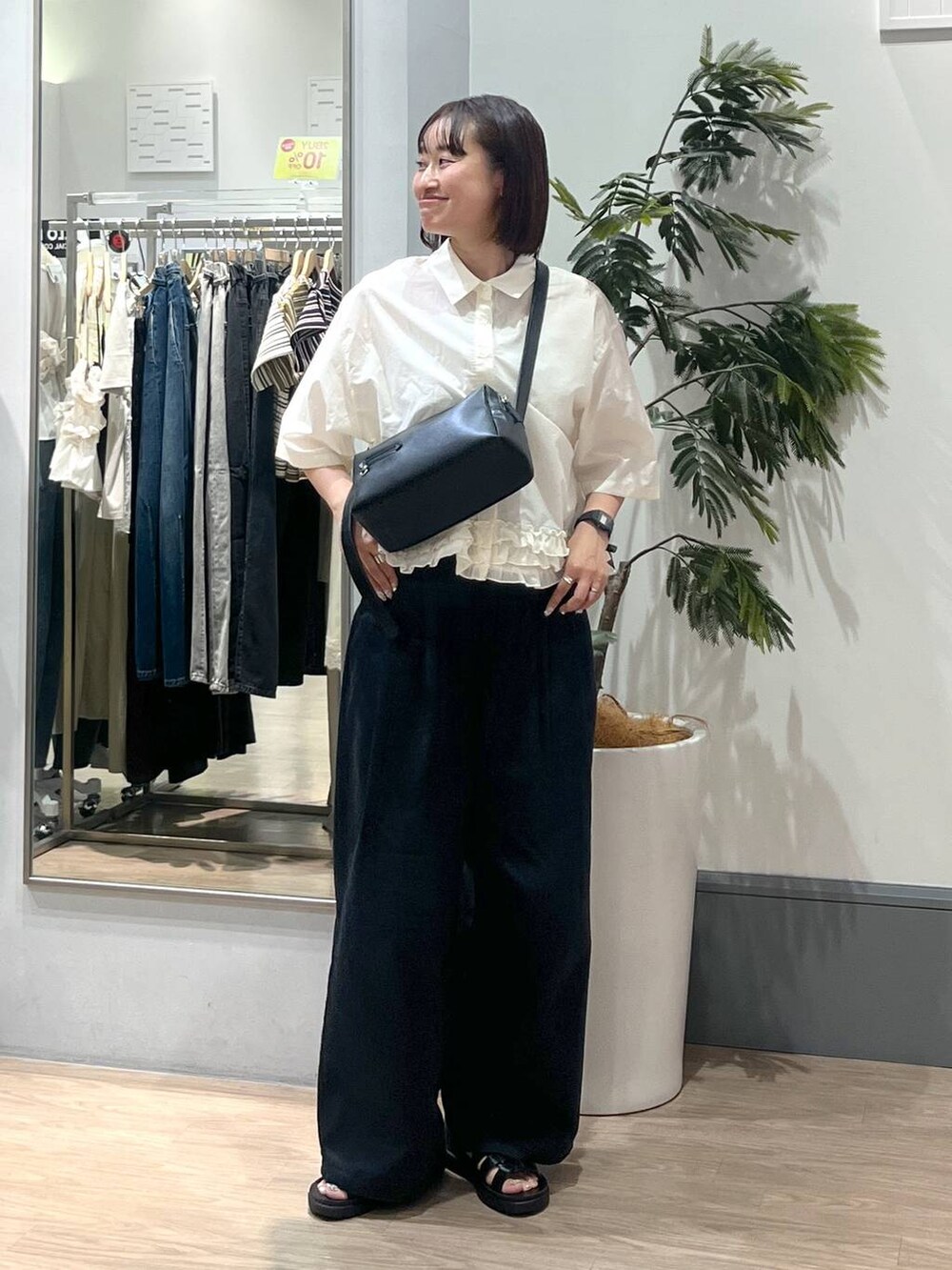 ブラック系のサンダル、ホワイト系のシャツ/ブラウス、ブラック系のショルダーバッグを着用したレディースの夏コーディネートの2枚目の写真