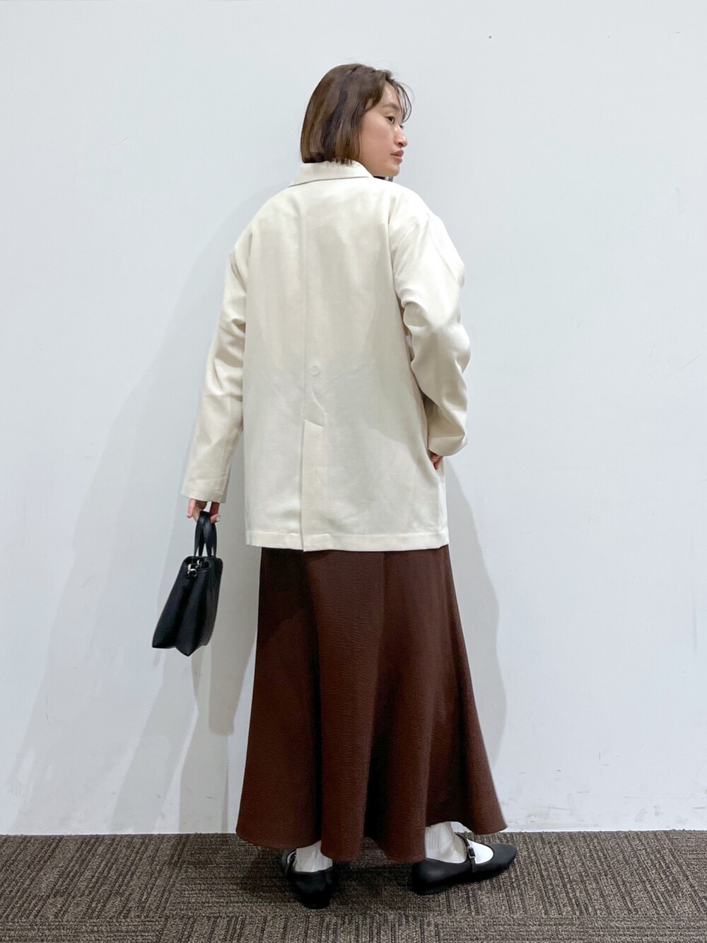 ホワイト系のジャケット/アウター、ホワイト系のトップス、ブラウン系のスカートを着用したレディースの春コーディネートの3枚目の写真