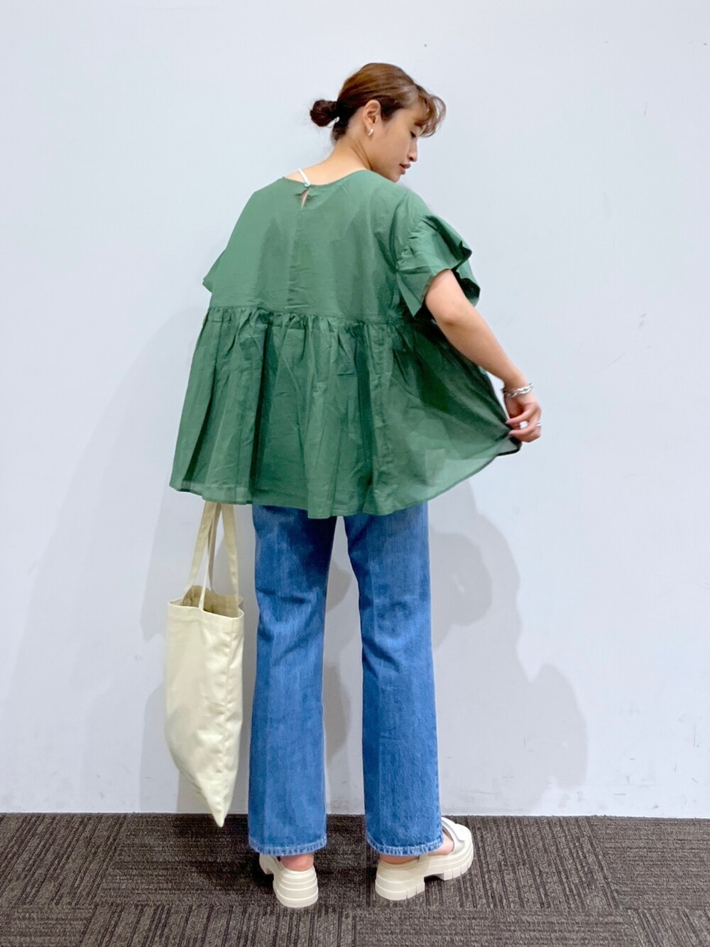 ブルー系のデニムパンツ、ホワイト系のトートバッグ、グリーン系のシャツ/ブラウスを着用したレディースの夏コーディネートの3枚目の写真