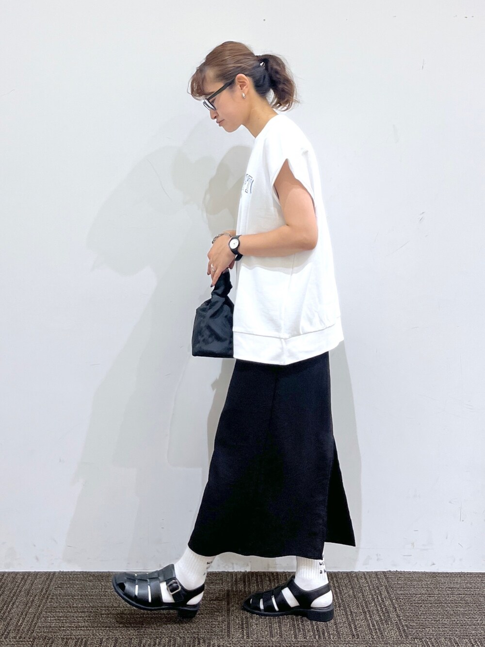 ブラック系のワンピース、ブラック系のショルダーバッグ、ホワイト系のTシャツ/カットソーを着用したレディースの夏コーディネートの2枚目の写真