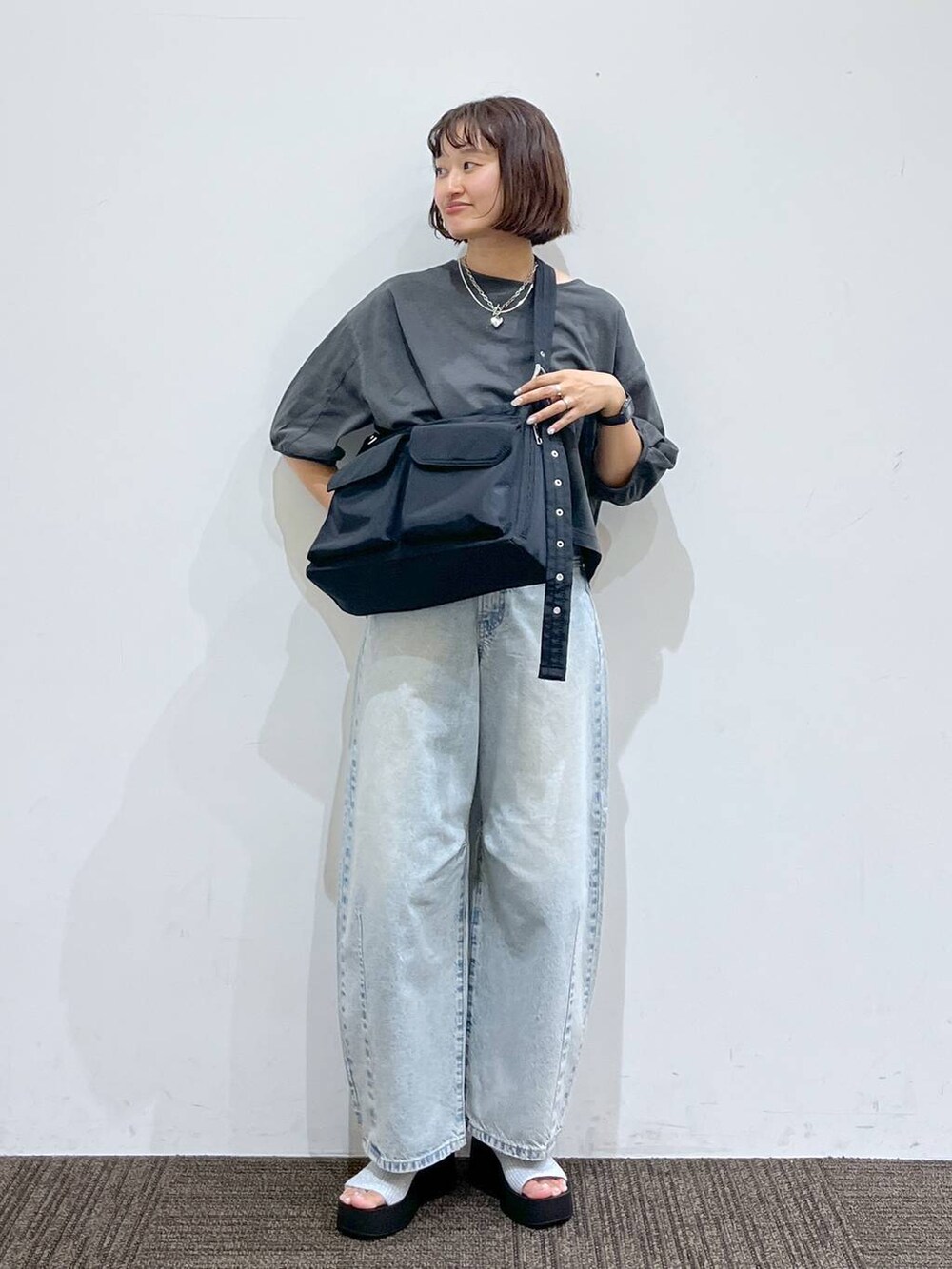 シルバー系のサンダル、ブラック系のショルダーバッグ、ブルー系のデニムパンツを着用したレディースの夏コーディネートの3枚目の写真