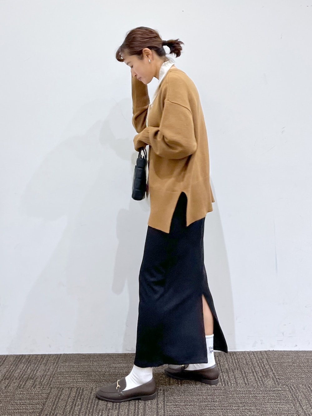 ブラック系のスカート、ホワイト系のトップス、ブラウン系のニット/セーターを着用したレディースの冬コーディネートの2枚目の写真