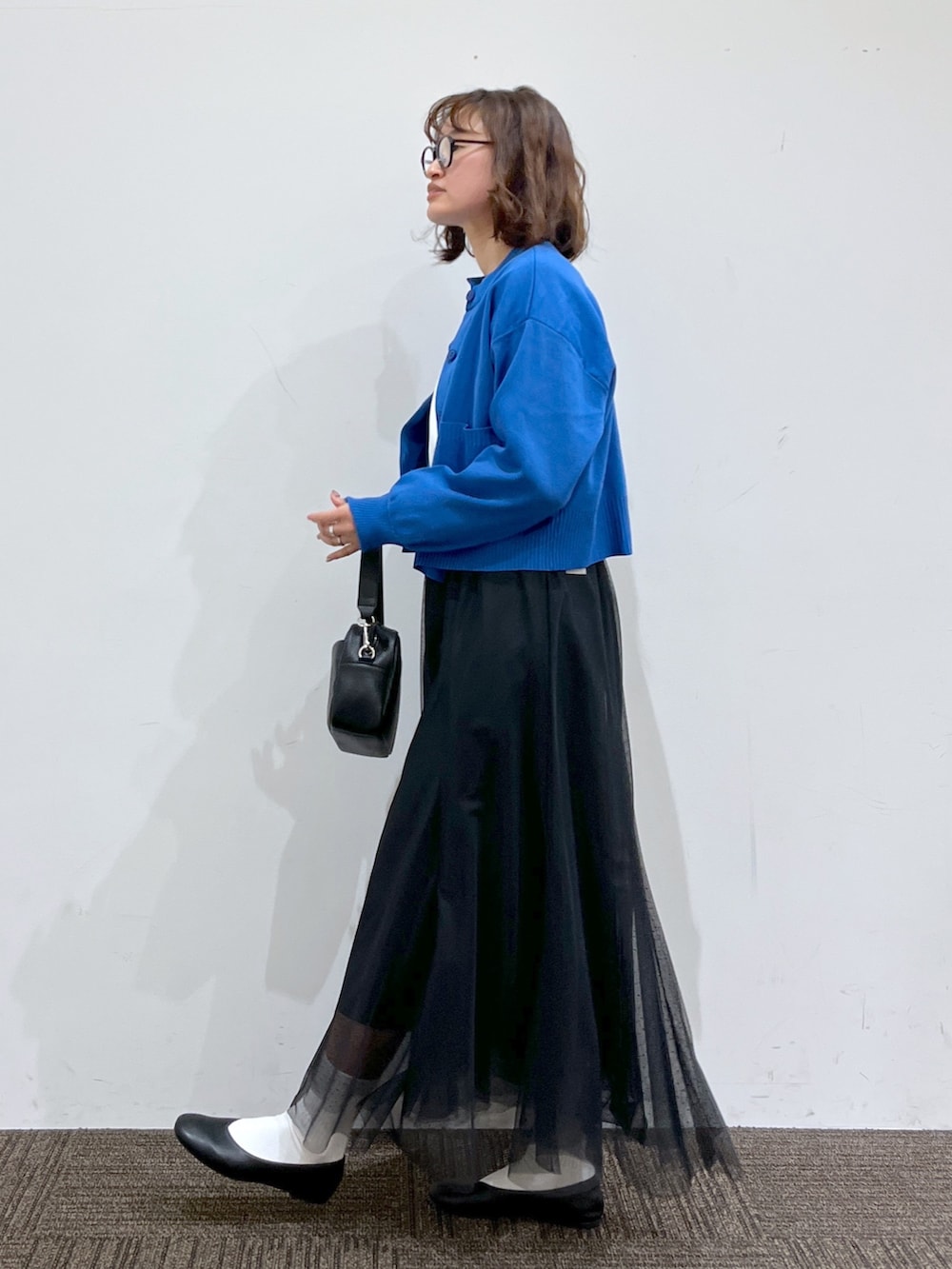 ブルー系のトップス、ブラック系のスカート、ホワイト系のトップスを着用したレディースの春コーディネートの2枚目の写真