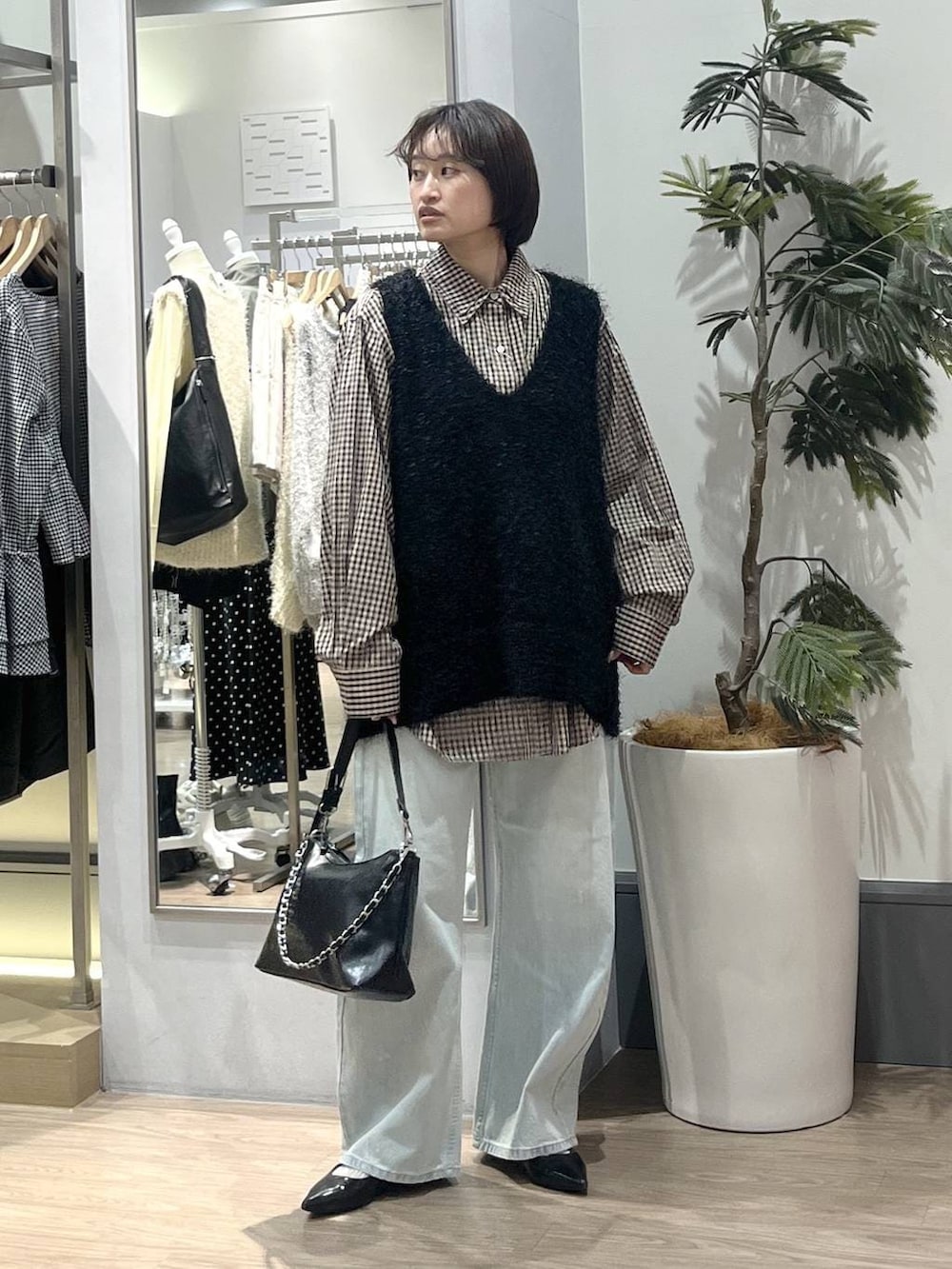 ブラック系のパンプス、ブルー系のデニムパンツ、ブラック系のショルダーバッグを着用したレディースの冬コーディネートの2枚目の写真