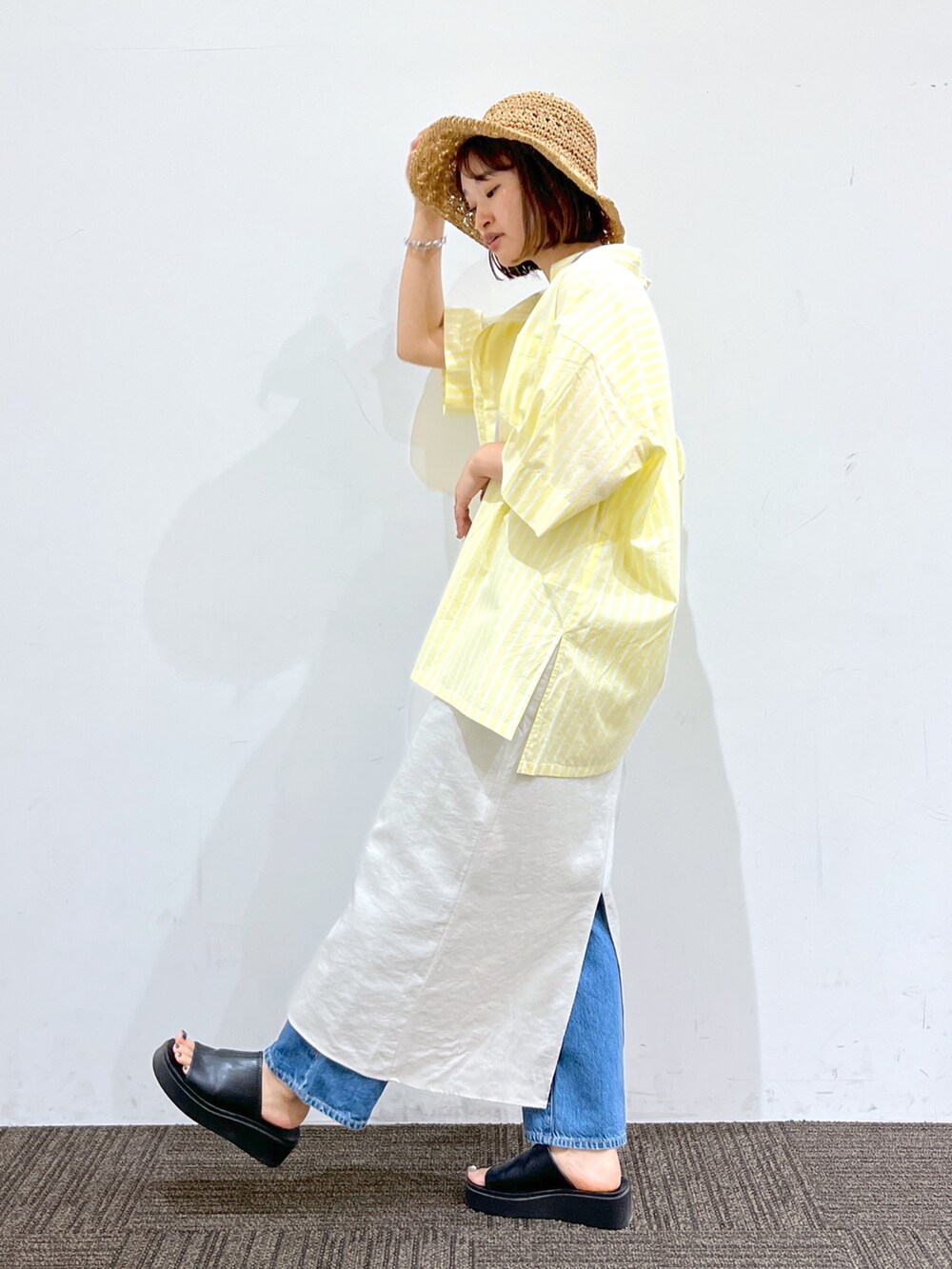 ホワイト系のワンピース、イエロー系のシャツ/ブラウス、ブルー系のデニムパンツを着用したレディースの夏コーディネートの2枚目の写真