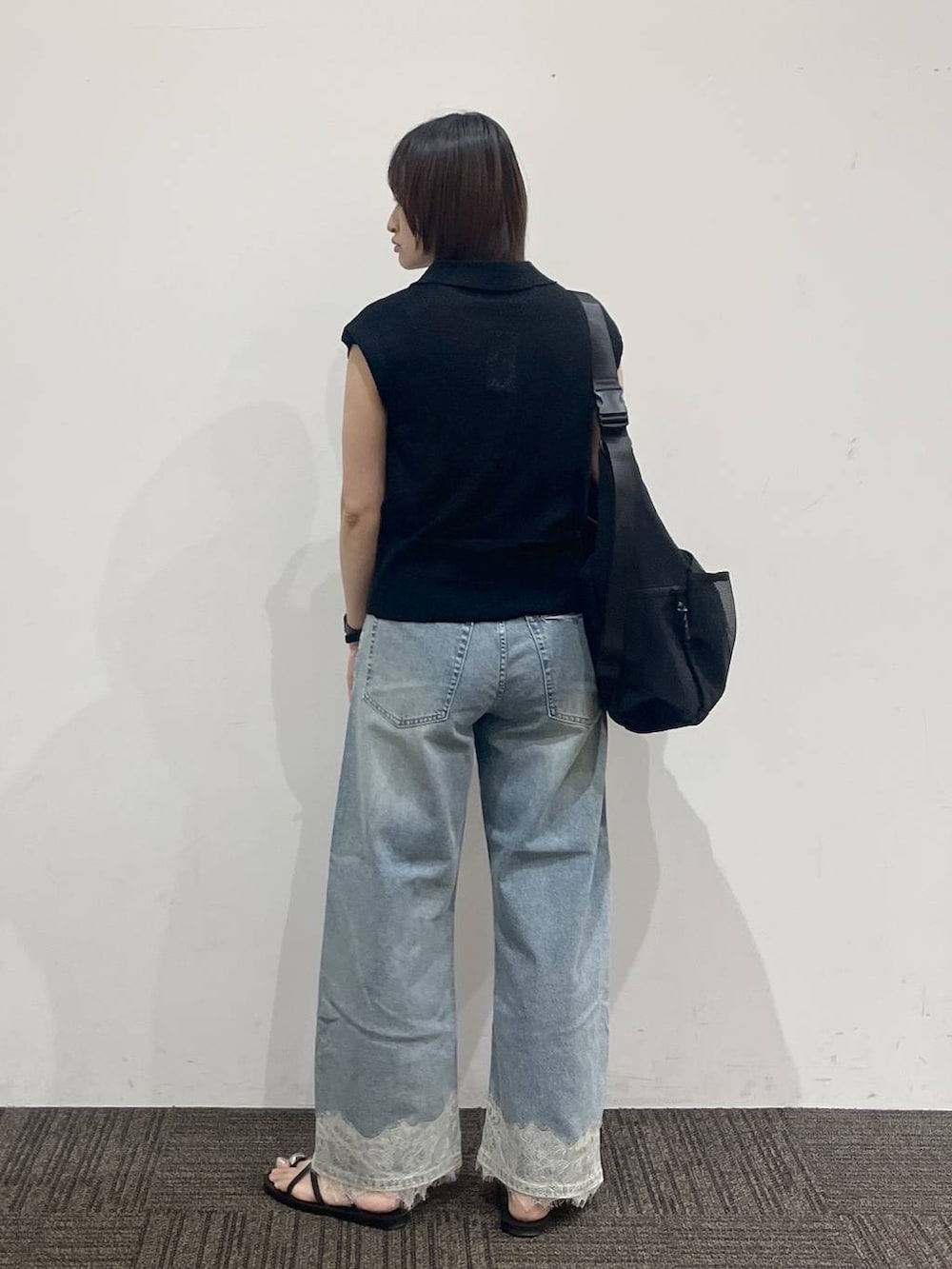 ブラック系のショルダーバッグ、ブラック系のベスト、ブルー系のデニムパンツを着用したレディースの夏コーディネートの4枚目の写真