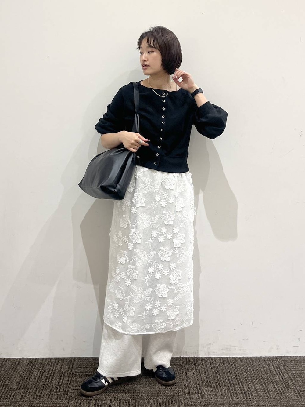 ブラック系のショルダーバッグ、グレー系のスウェットパンツ、ホワイト系のスカートを着用したレディースの春コーディネートの2枚目の写真