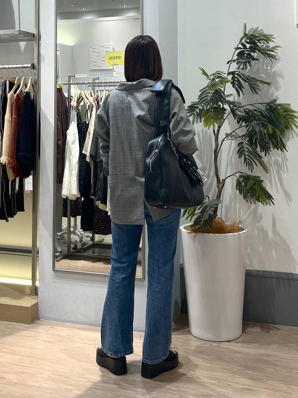 ブラック系のサンダル、グレー系のテーラードジャケット、ブルー系のデニムパンツを着用したレディースの秋コーディネートの5枚目の写真