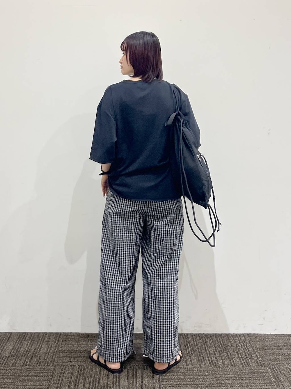ブラック系のTシャツ/カットソー、ブラック系のサンダル、ブラック系のバックパック/リュックを着用したレディースの夏コーディネートの4枚目の写真