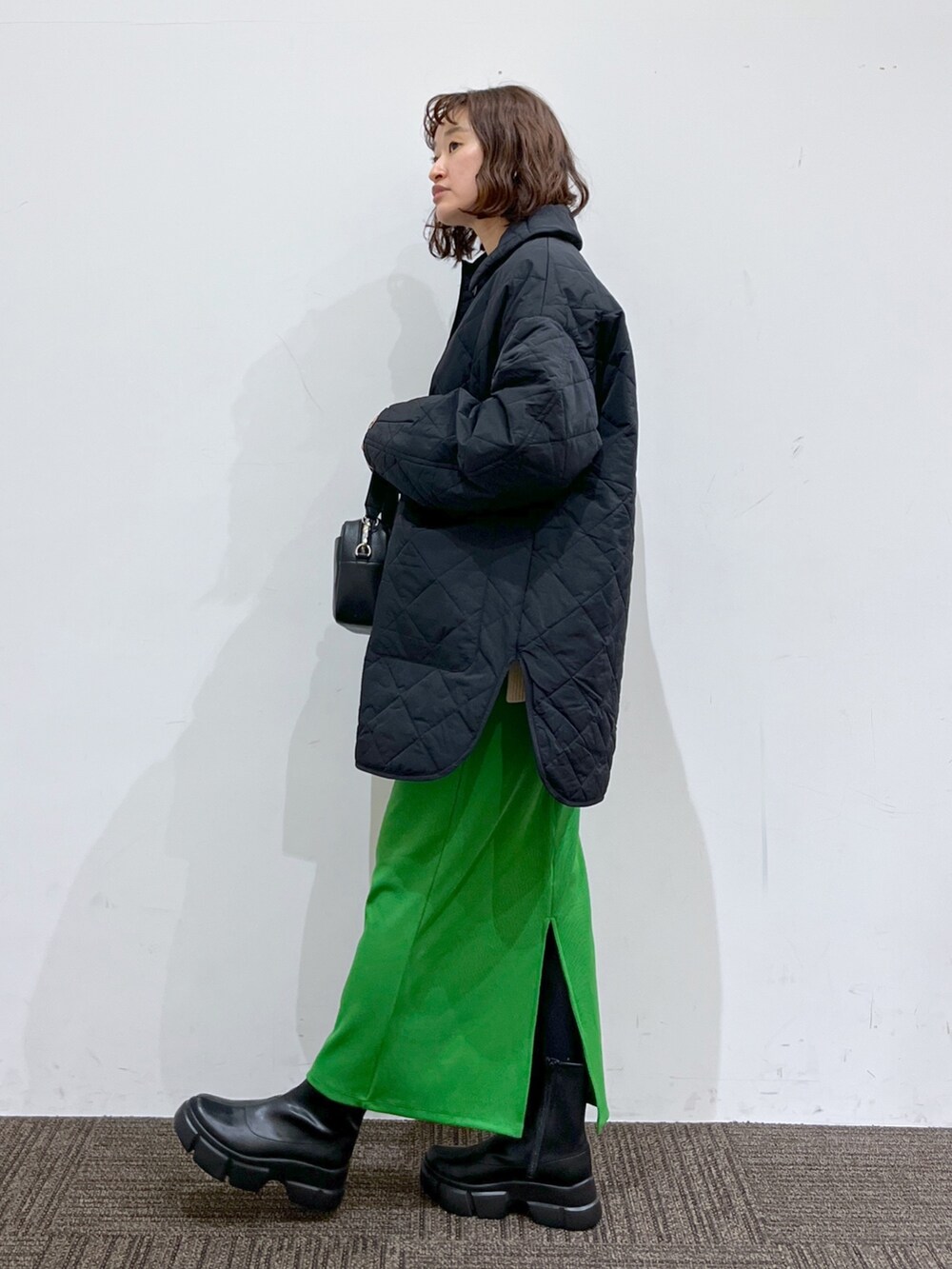 ブラック系のミリタリージャケット、ホワイト系のニット/セーター、グリーン系のスカートを着用したレディースの冬コーディネートの2枚目の写真