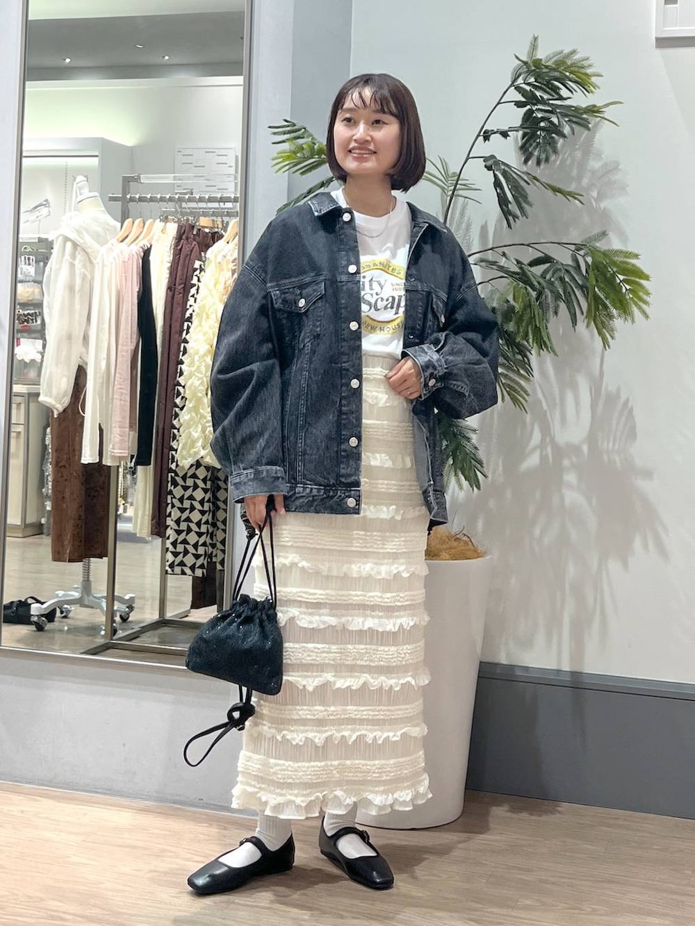 ホワイト系のTシャツ/カットソー、ホワイト系のスカート、ブラック系のデニムジャケットを着用したレディースの秋コーディネートの2枚目の写真