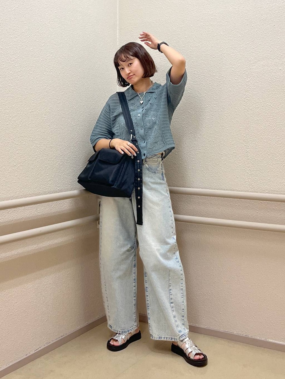 ブルー系のデニムパンツ、グリーン系のニット/セーター、シルバー系のスニーカーを着用したレディースの夏コーディネートの2枚目の写真