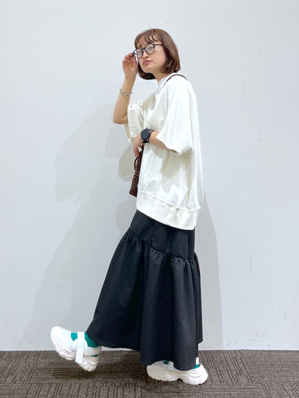 ホワイト系のTシャツ/カットソー、ブラック系のスカート、ゴールド系のバッグを着用したレディースの春コーディネートの2枚目の写真