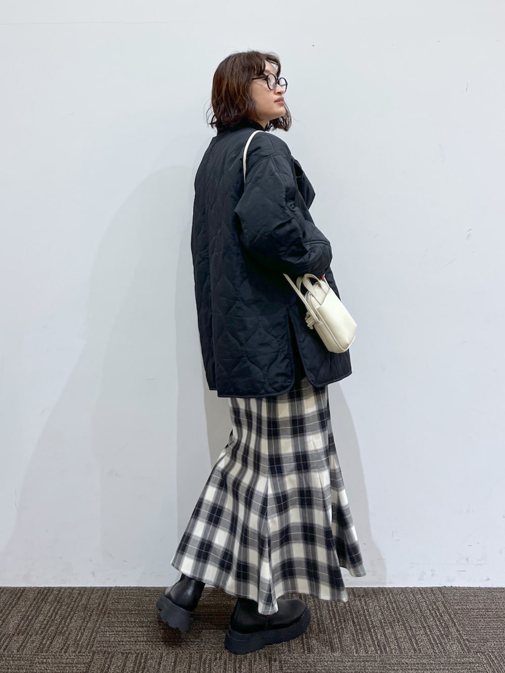 ブラック系のブーツ、ホワイト系のショルダーバッグ、ブラック系のスカートを着用したレディースの冬コーディネートの4枚目の写真