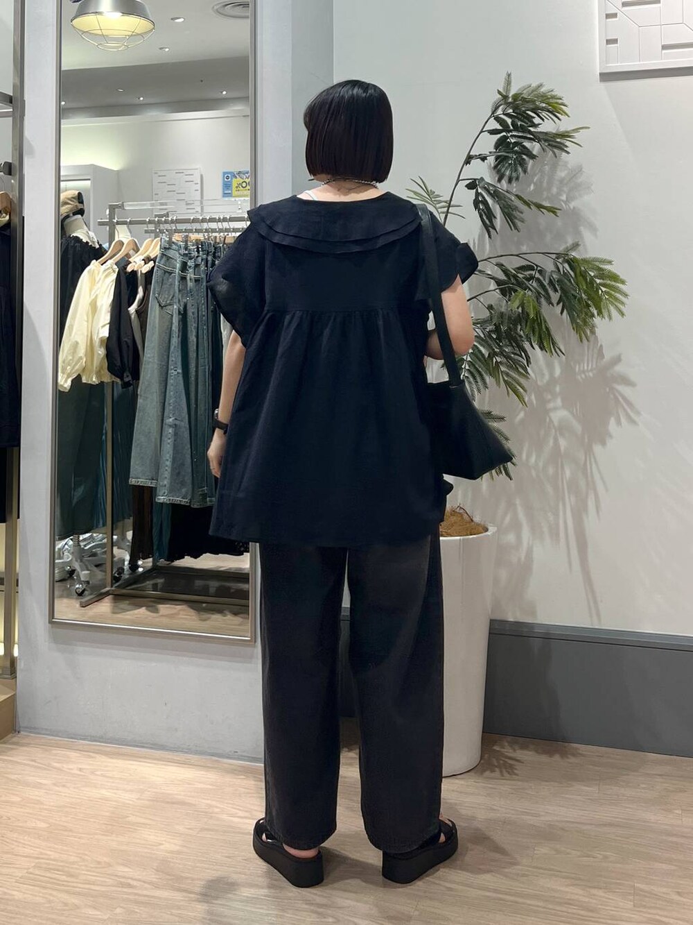 ブラック系のサンダル、ブラック系のデニムパンツ、ブラック系のショルダーバッグを着用したレディースの春コーディネートの5枚目の写真