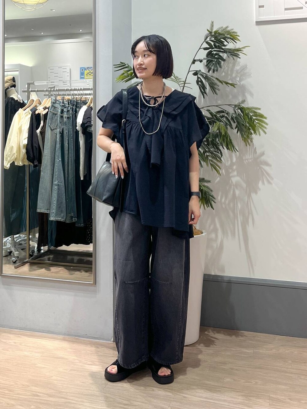 ブラック系のサンダル、ブラック系のデニムパンツ、ブラック系のショルダーバッグを着用したレディースの春コーディネートの2枚目の写真