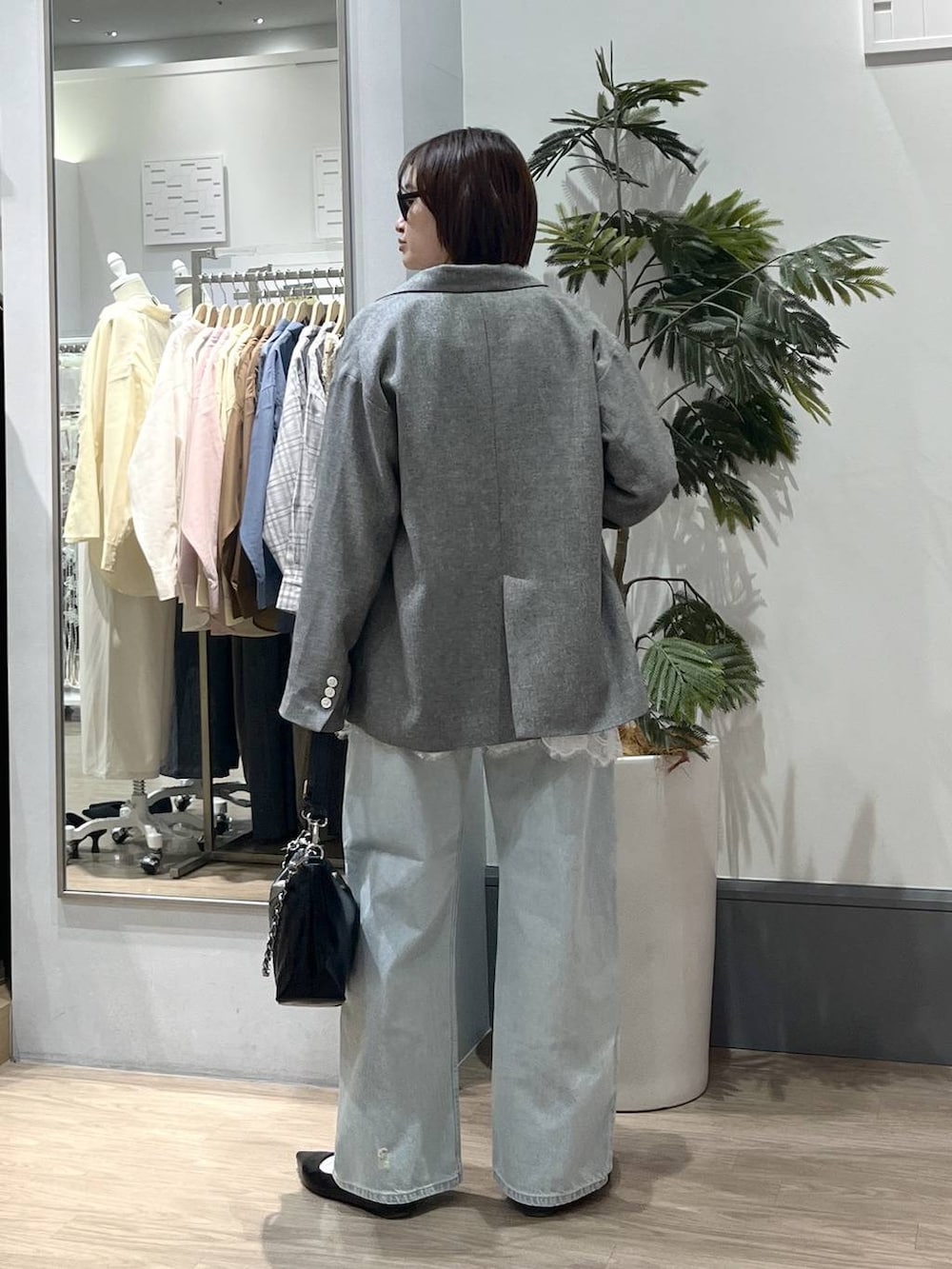 ブラック系のパンプス、グレー系のテーラードジャケット、ブルー系のデニムパンツを着用したレディースの春コーディネートの4枚目の写真