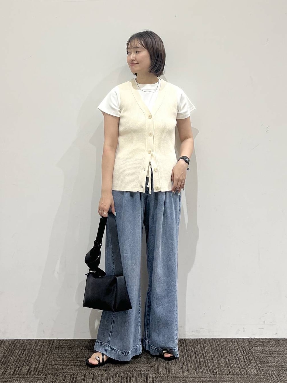 ブルー系のデニムパンツ、ホワイト系のTシャツ/カットソー、ブラック系のサンダルを着用したレディースの夏コーディネートの3枚目の写真