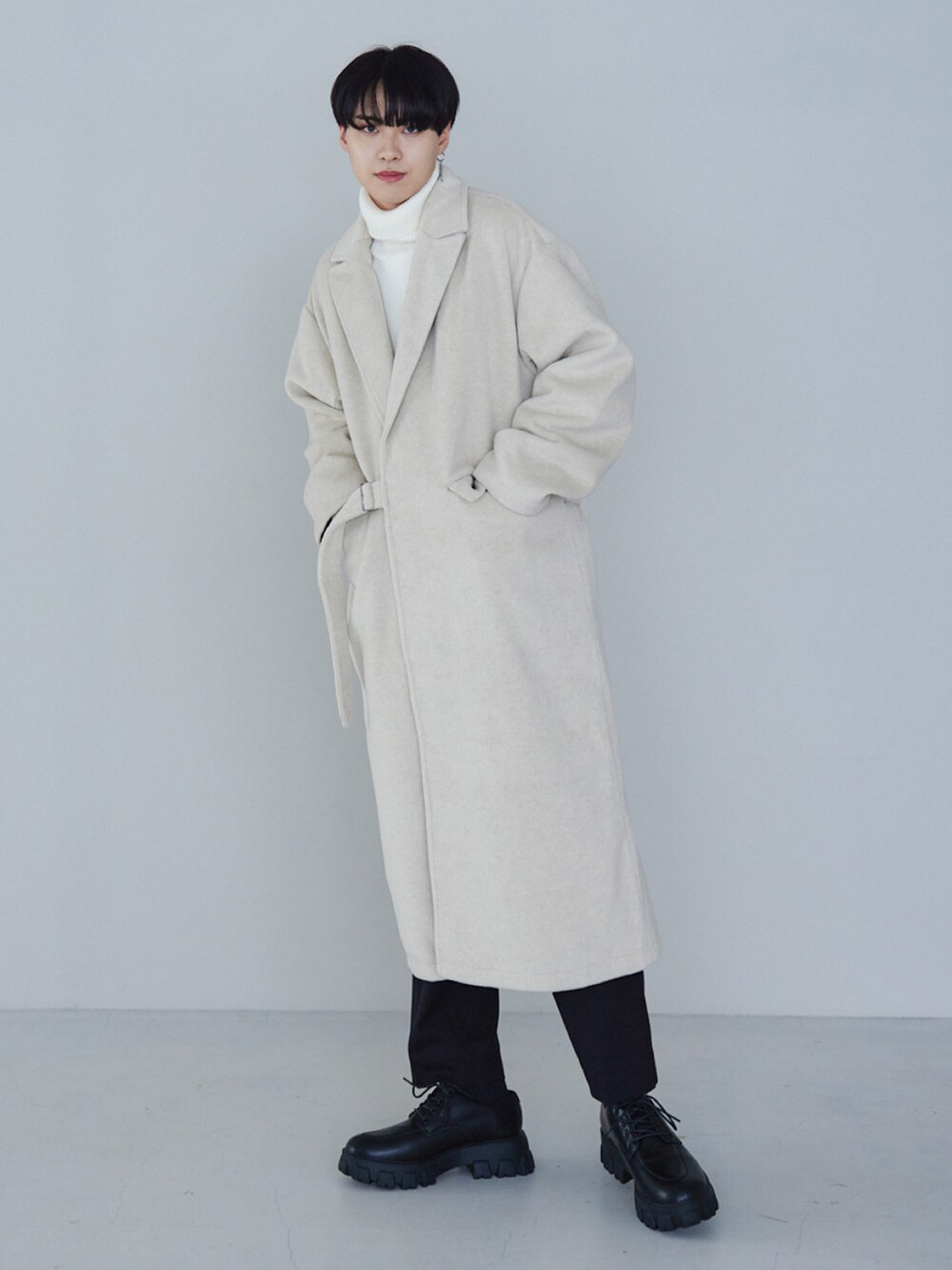 ベージュ系のチェスターコート、ベージュ系のニット/セーター、ブラック系のその他パンツを着用したメンズの冬コーディネートの3枚目の写真