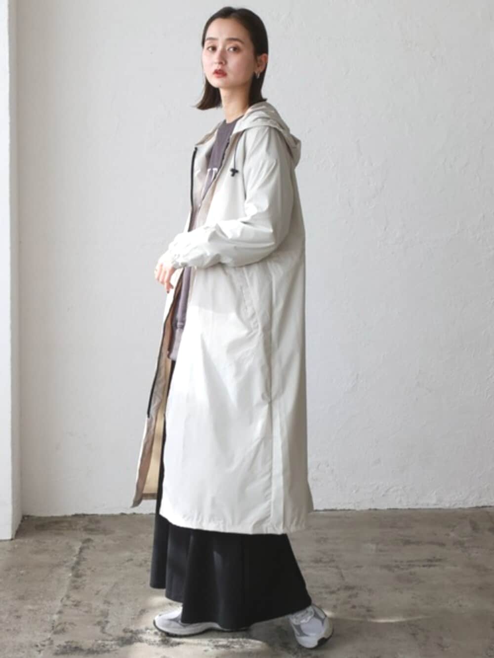 グレー系のスウェット、ベージュ系のレインコート/ポンチョを着用したレディースの秋コーディネートの3枚目の写真