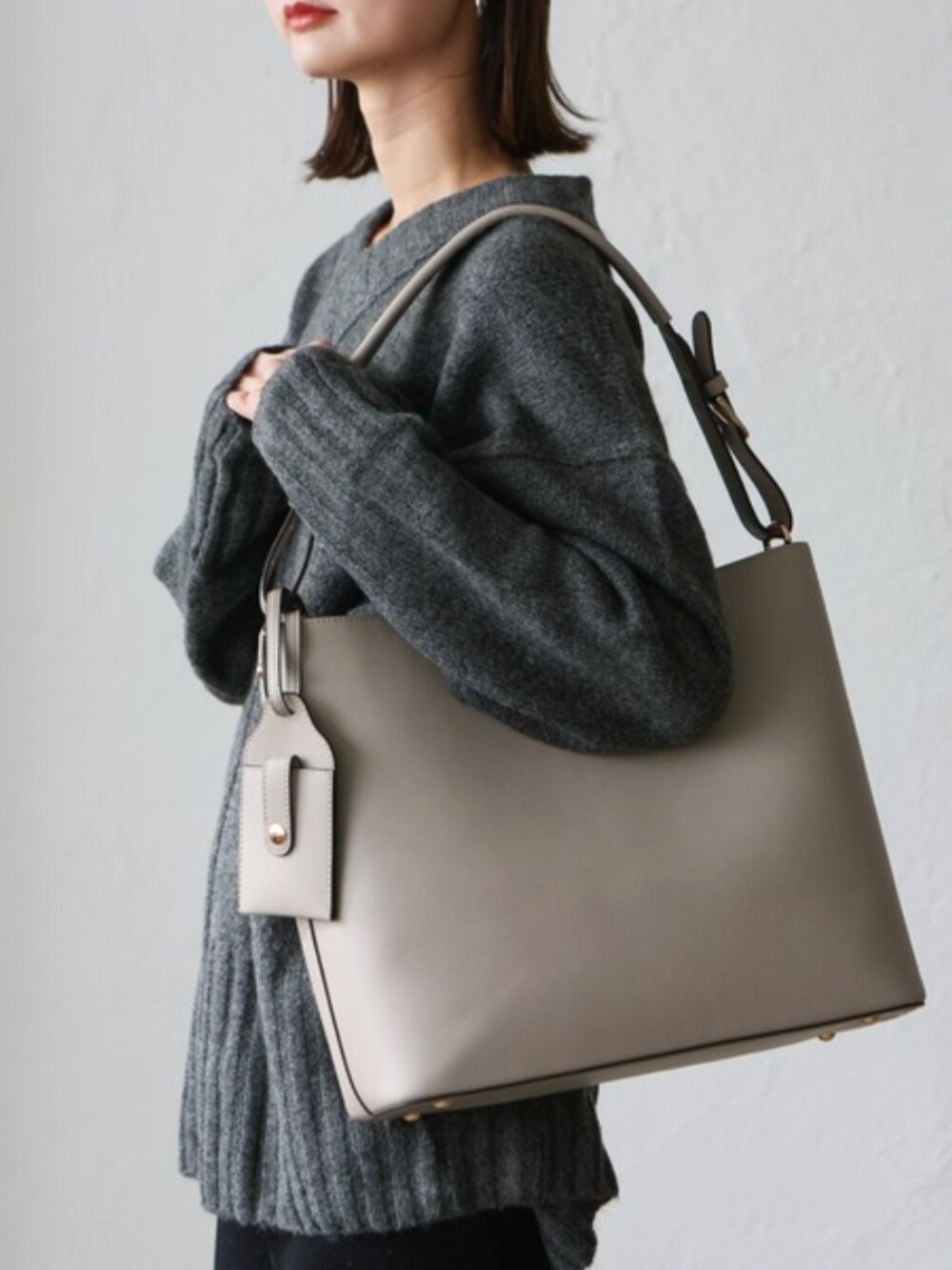 グレー系のニット/セーター、グレー系のトートバッグを着用したレディースの秋コーディネートの3枚目の写真