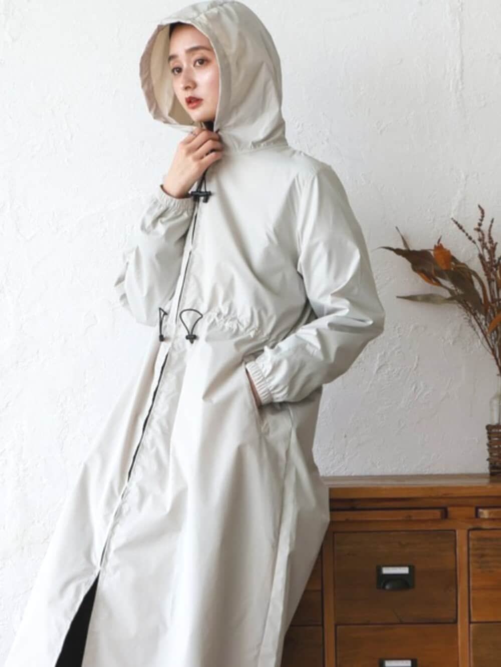 グレー系のスウェット、ベージュ系のレインコート/ポンチョを着用したレディースの秋コーディネートの4枚目の写真