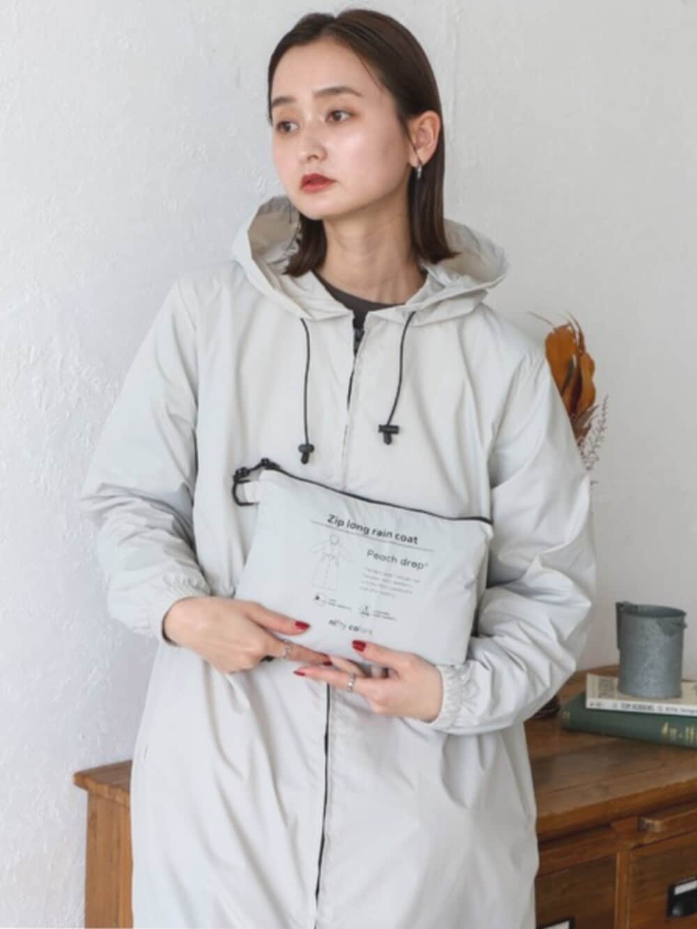 グレー系のスウェット、ベージュ系のレインコート/ポンチョを着用したレディースの秋コーディネートの5枚目の写真