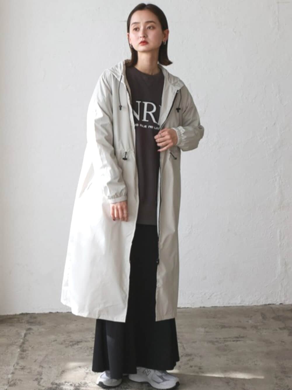 グレー系のスウェット、ベージュ系のレインコート/ポンチョを着用したレディースの秋コーディネートの2枚目の写真