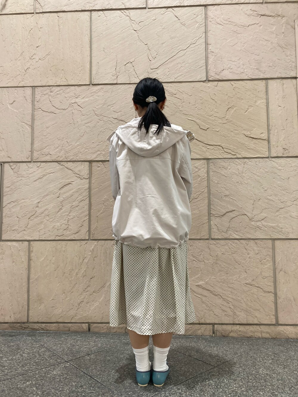 グレー系のマウンテンパーカー、ホワイト系のワンピース、ブラウン系のショルダーバッグを着用したレディースの春コーディネートの3枚目の写真