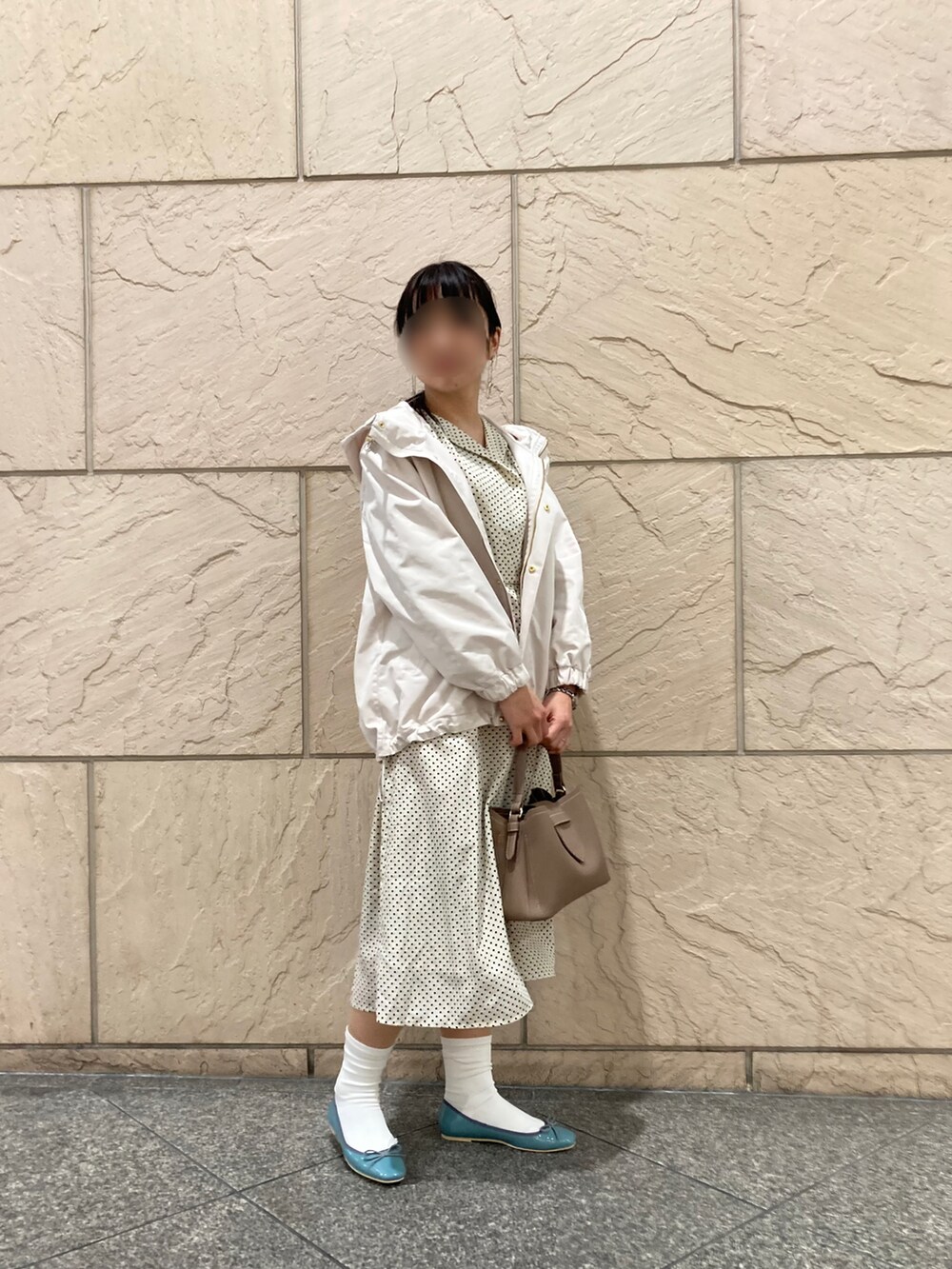 グレー系のマウンテンパーカー、ホワイト系のワンピース、ブラウン系のショルダーバッグを着用したレディースの春コーディネートの2枚目の写真